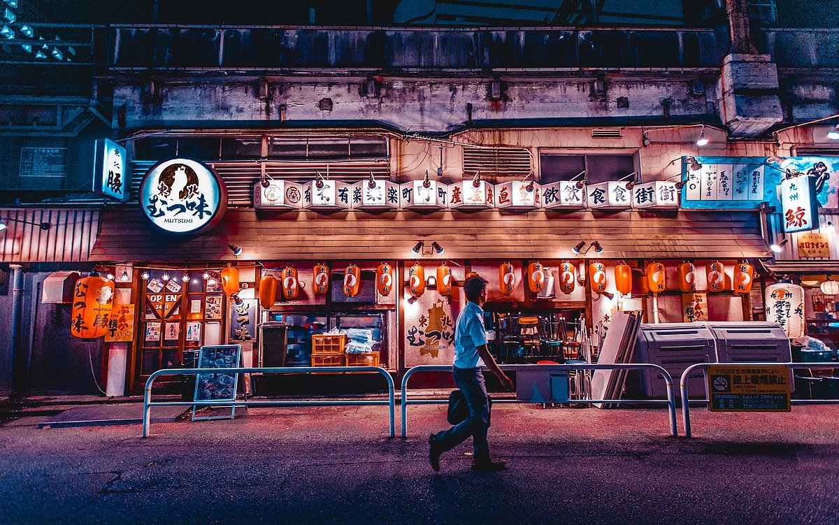 In einer chinesischen Stadt läuft ein Mann nachts an einem hell erleuchtetem Kino vorbei.