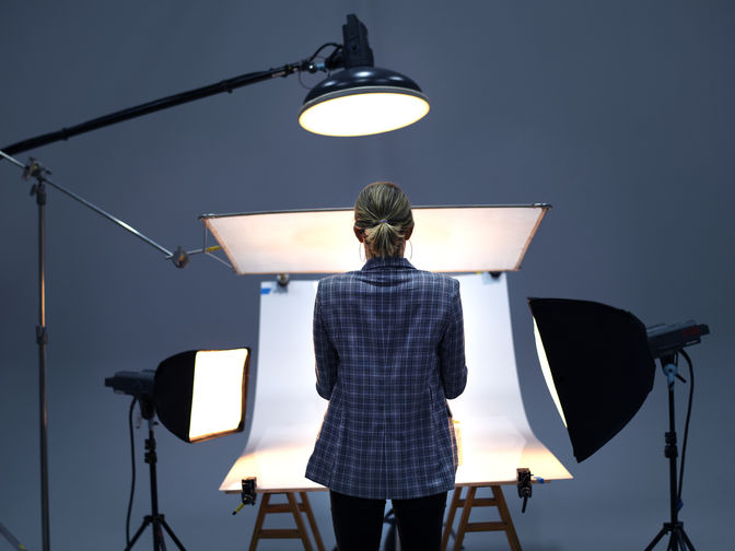 Rückansicht einer Fotografin, die vor einer Hohlkehle steht, welche von mehreren Scheinwerfern beleuchtet wird.