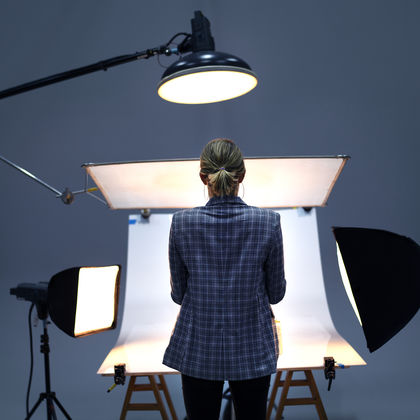 Rückansicht einer Fotografin, die vor einer Hohlkehle steht, welche von mehreren Scheinwerfern beleuchtet wird.