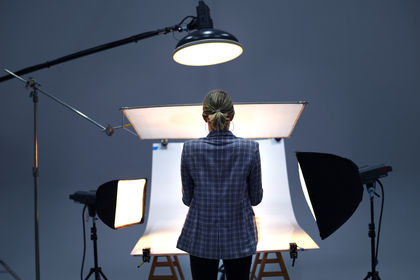 Rückansicht einer Fotografin, die vor einer Hohlkehle steht, welche von mehreren Scheinwerfern beleuchtet wird.